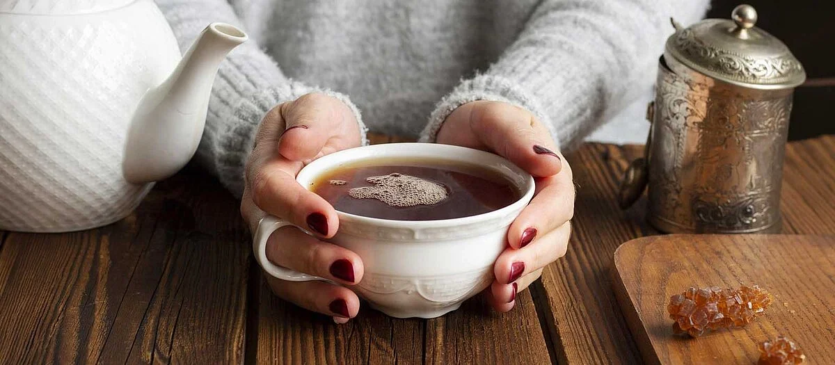 femme tenant une tasse de thé dans ses mains